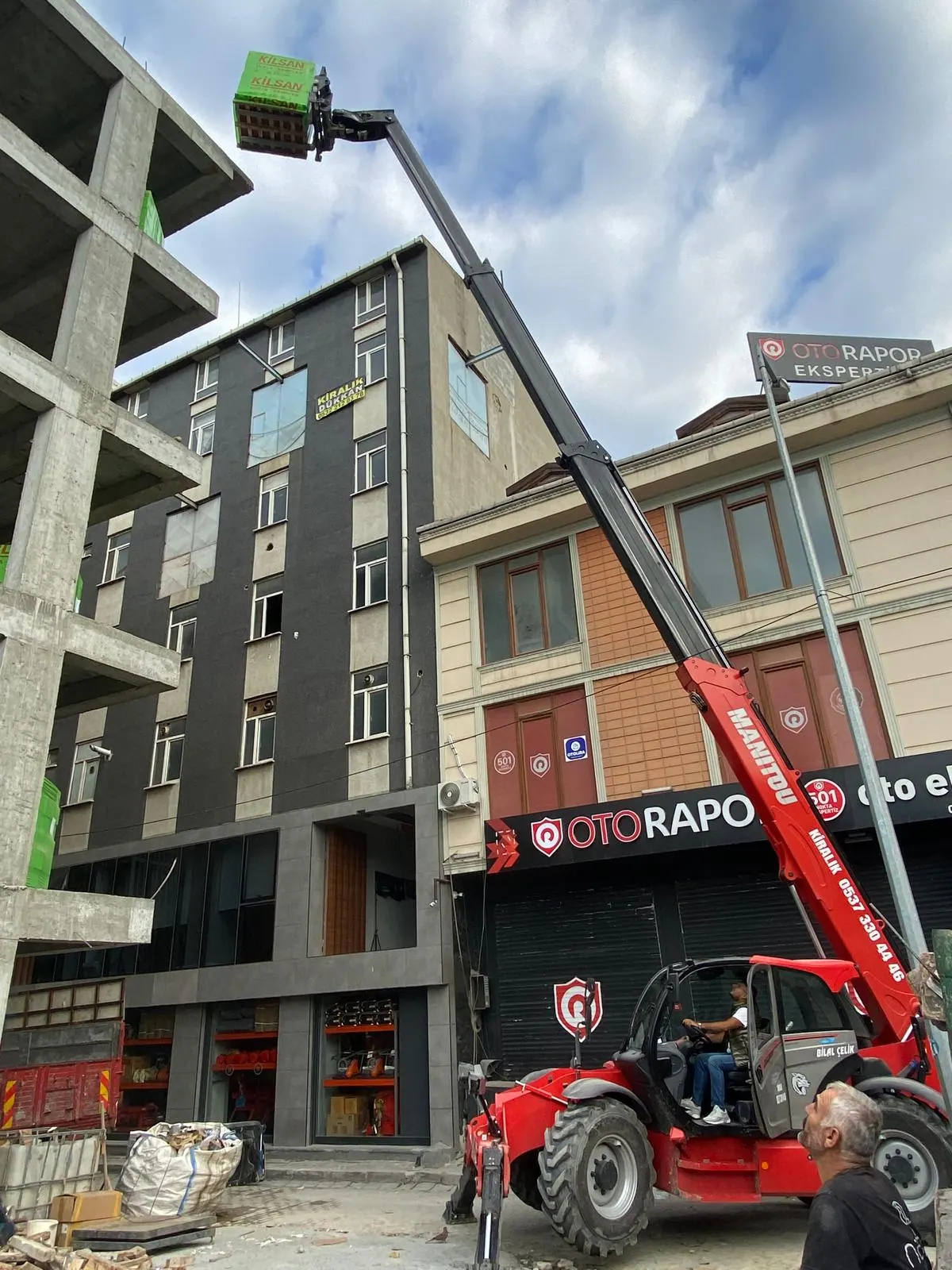 Ticari binanın önünde çalışan Manitou
